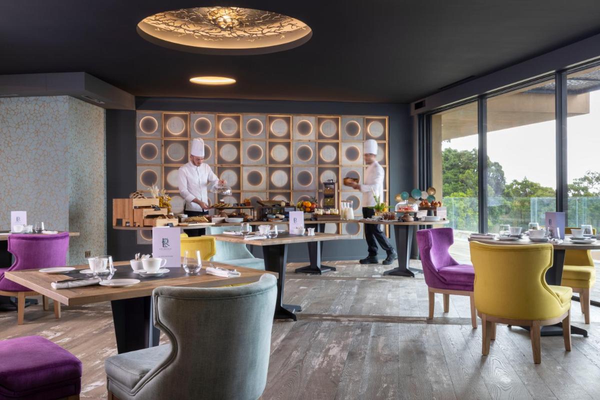 un restaurant avec des tables et des chaises et un chef en arrière-plan dans l'établissement Les Regalia Hôtel & Spa, à Sainte-Lucie de Porto-Vecchio