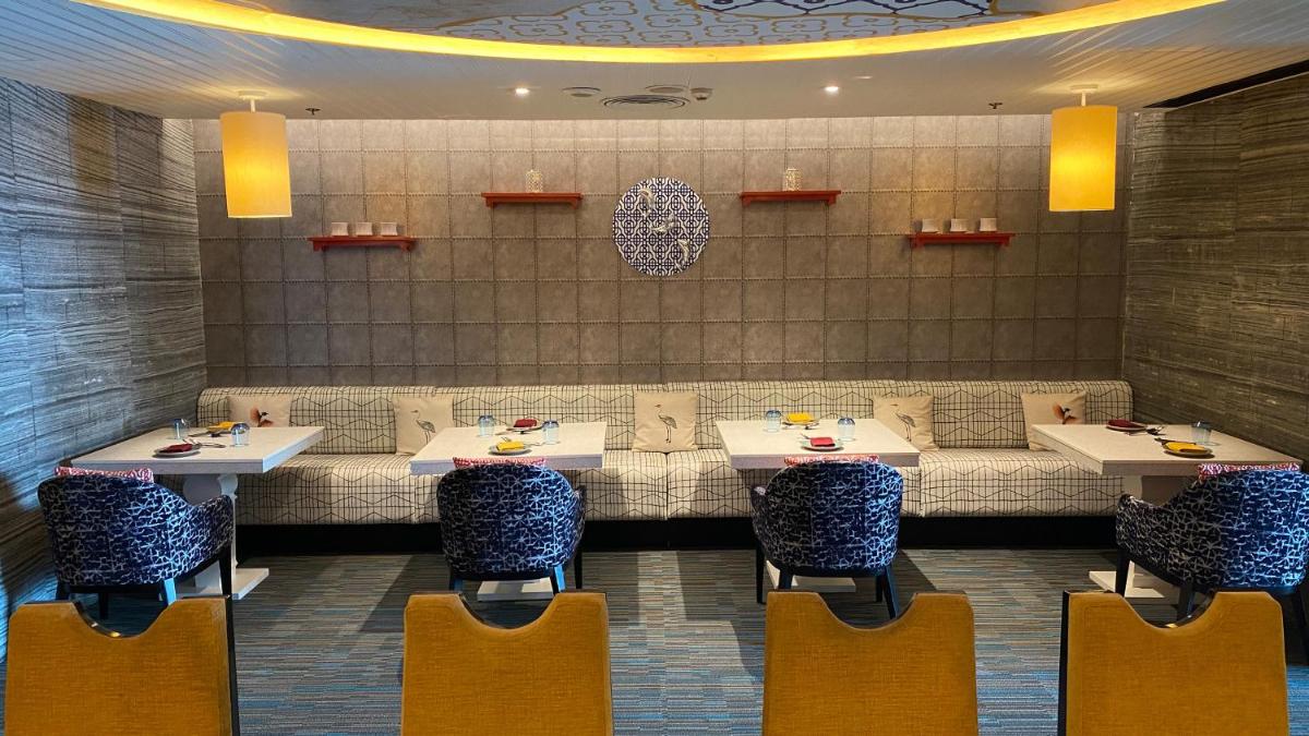 a dining room with two tables and chairs at Crowne Plaza Kochi by IHG in Cochin