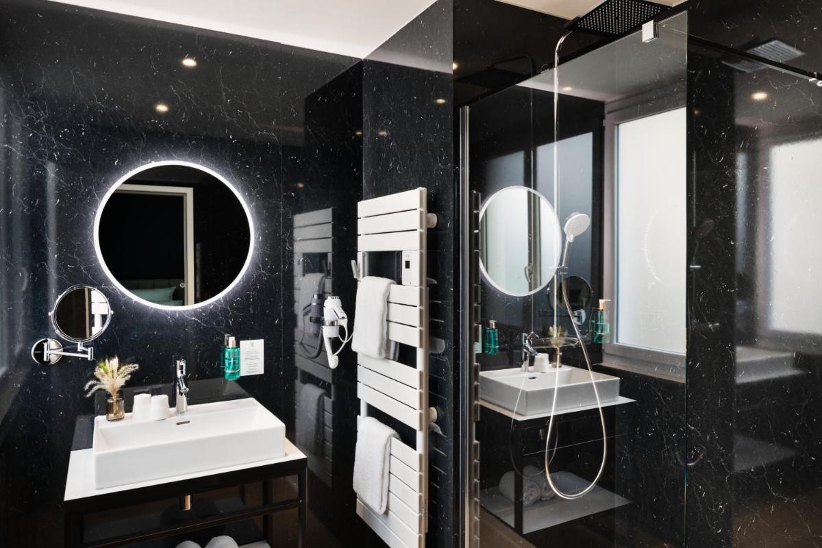 La salle de bains noire est pourvue de deux lavabos et de miroirs. dans l'établissement Hôtel & Spa Le Maury, Vannes, The Originals Boutique, à Vannes