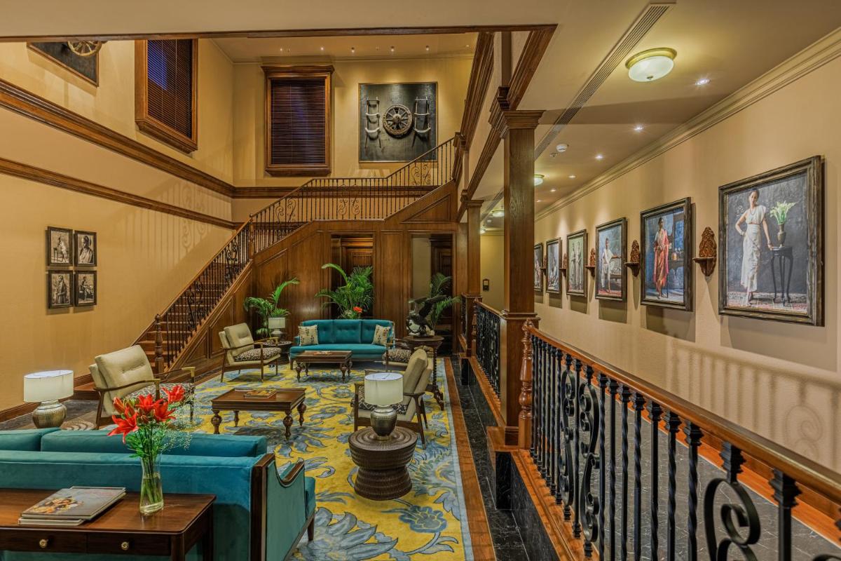 a living room with a staircase with blue furniture at Raajkutir - IHCL SeleQtions in Kolkata