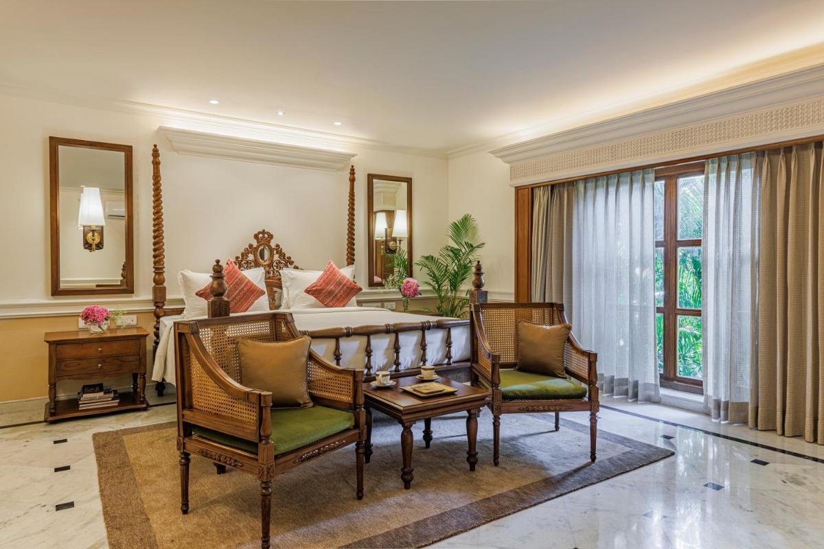a bedroom with a bed with two chairs and a table at Raajkutir - IHCL SeleQtions in Kolkata