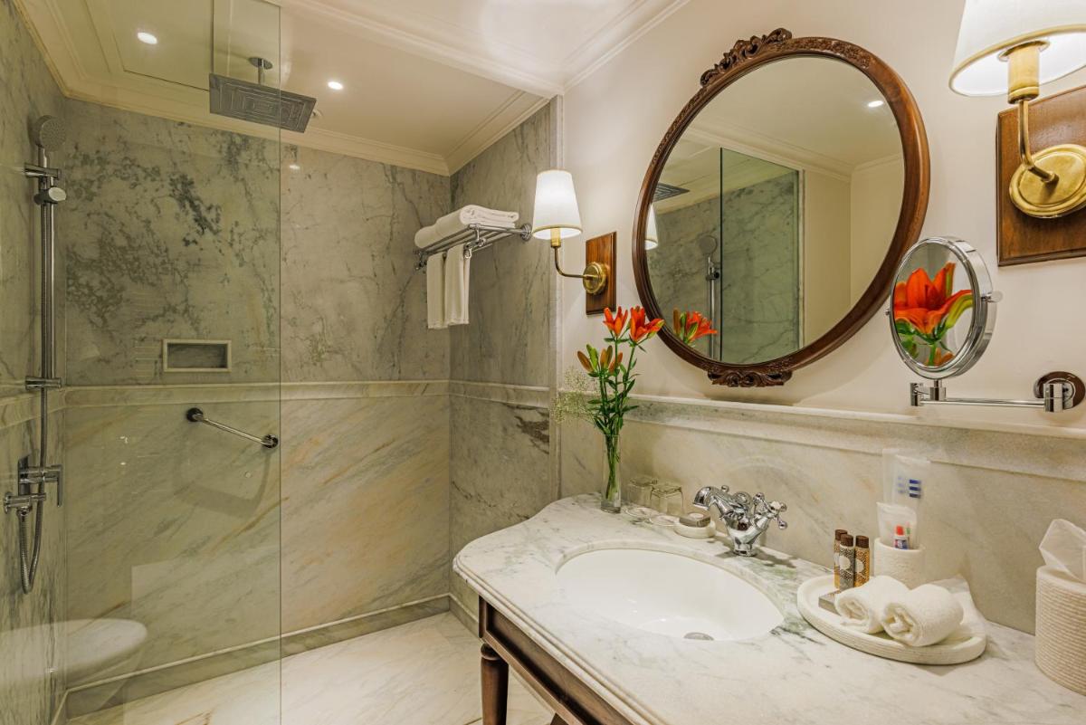 a bathroom with a shower and a sink and a mirror at Raajkutir - IHCL SeleQtions in Kolkata a bathroom with a shower and a sink and a mirror at Raajkutir - IHCL SeleQtions in Kolkata