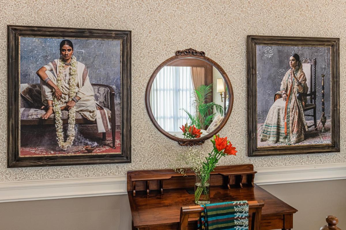 two framed portraits of a man and a woman on a wall at Raajkutir - IHCL SeleQtions in Kolkata