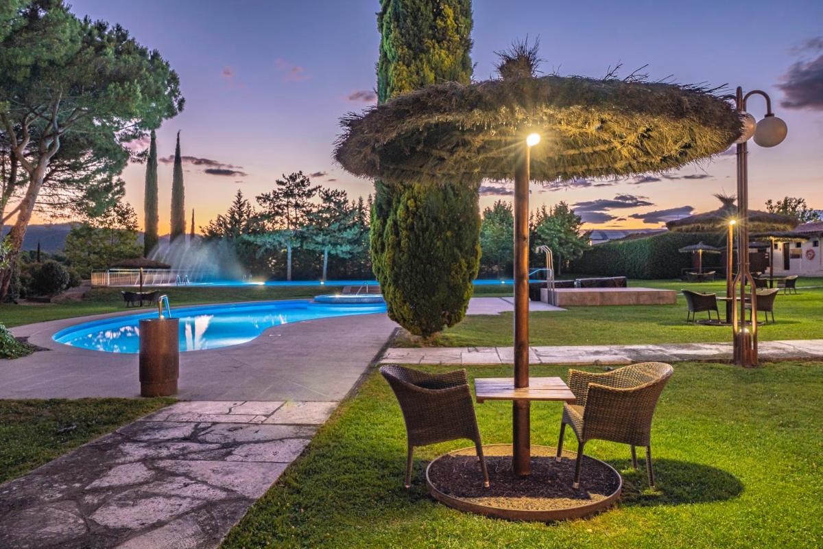 una mesa y sillas bajo una sombrilla junto a una piscina en Hotel Mas Solà, en Santa Coloma de Farners