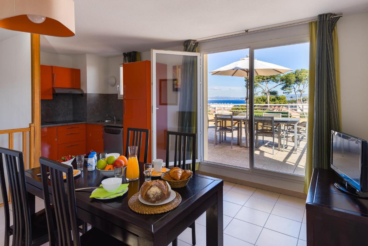 - une cuisine et une salle à manger avec une table et une vue sur l'océan dans l'établissement Lagrange Vacances Les Terrasses des Embiez, à Six-Fours-les-Plages