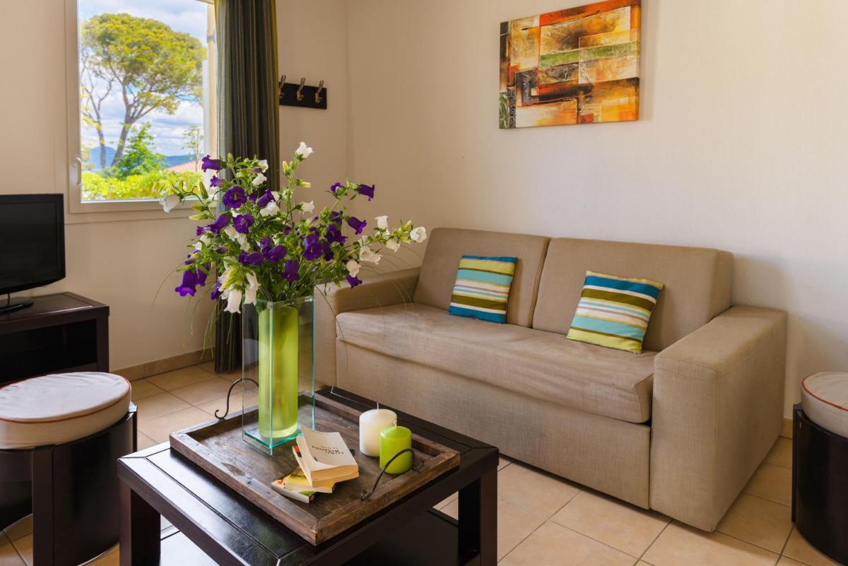 - un salon avec un canapé et des fleurs sur une table dans l'établissement Lagrange Vacances Les Terrasses des Embiez, à Six-Fours-les-Plages