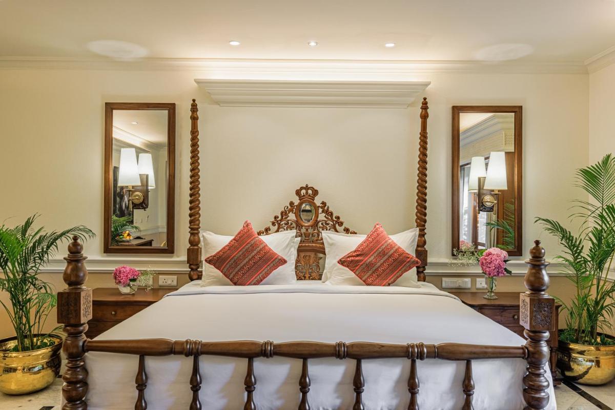 a bedroom with a large bed with two mirrors at Raajkutir - IHCL SeleQtions in Kolkata