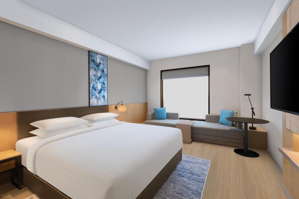 a bedroom with a large white bed and a couch at Fairfield by Marriott Dehradun in Dehradun