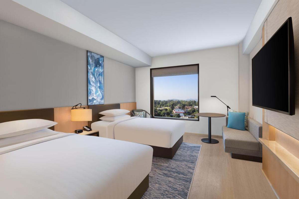 a hotel room with a bed and a flat screen tv at Fairfield by Marriott Dehradun in Dehradun