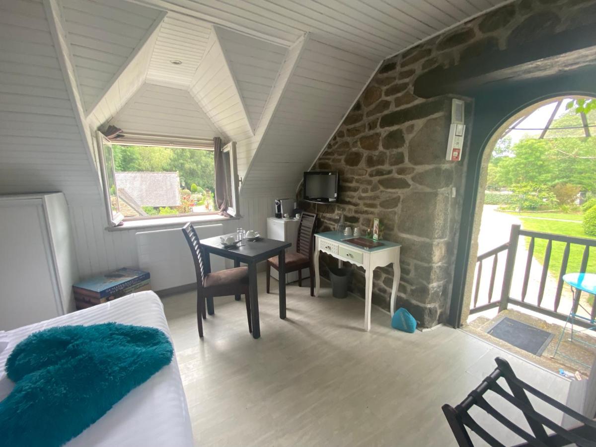 Cette chambre est dotée d'une table, de chaises et d'un mur en pierre. dans l'établissement Les Moulins Du Duc ÉCOLODGE, à Moëlan-sur-Mer
