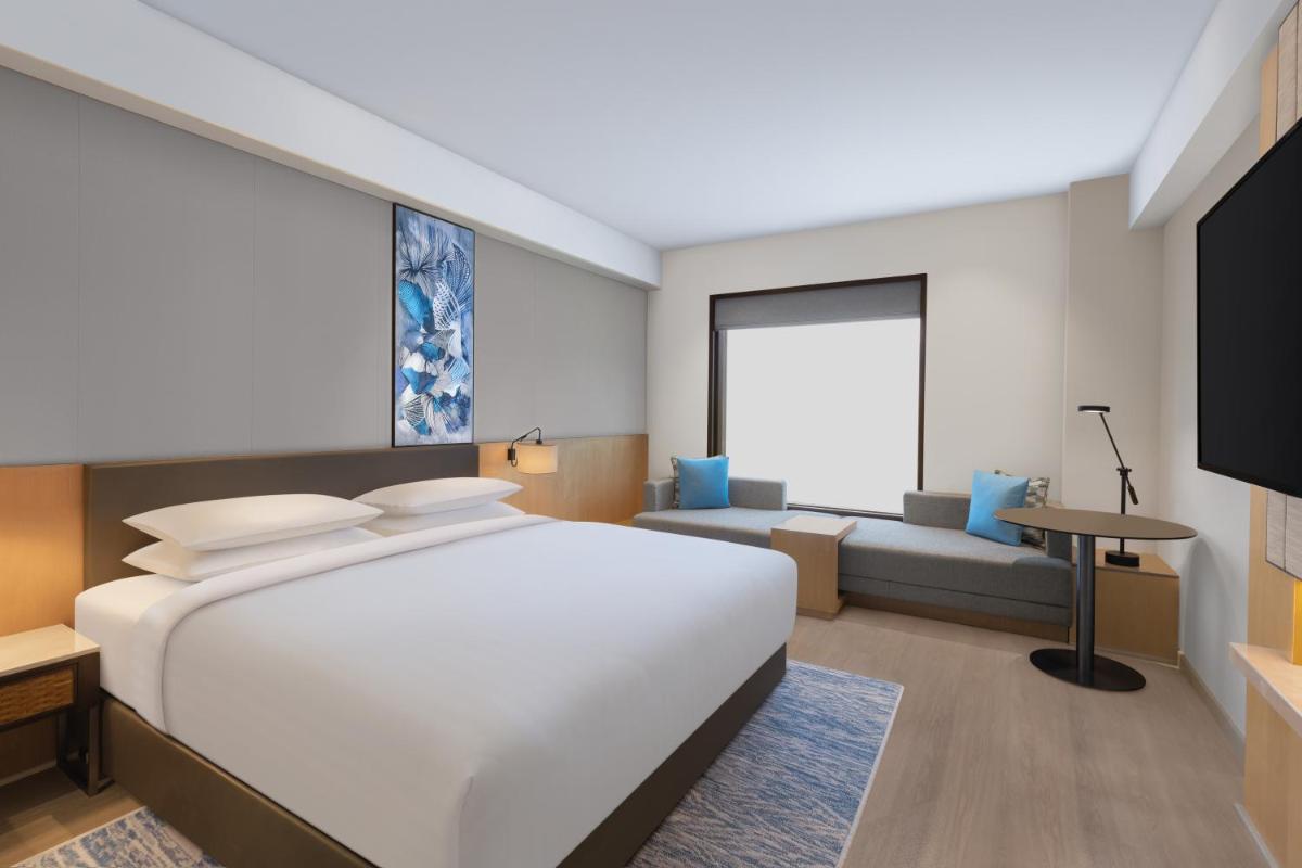a bedroom with a large white bed and a couch at Fairfield by Marriott Dehradun in Dehradun