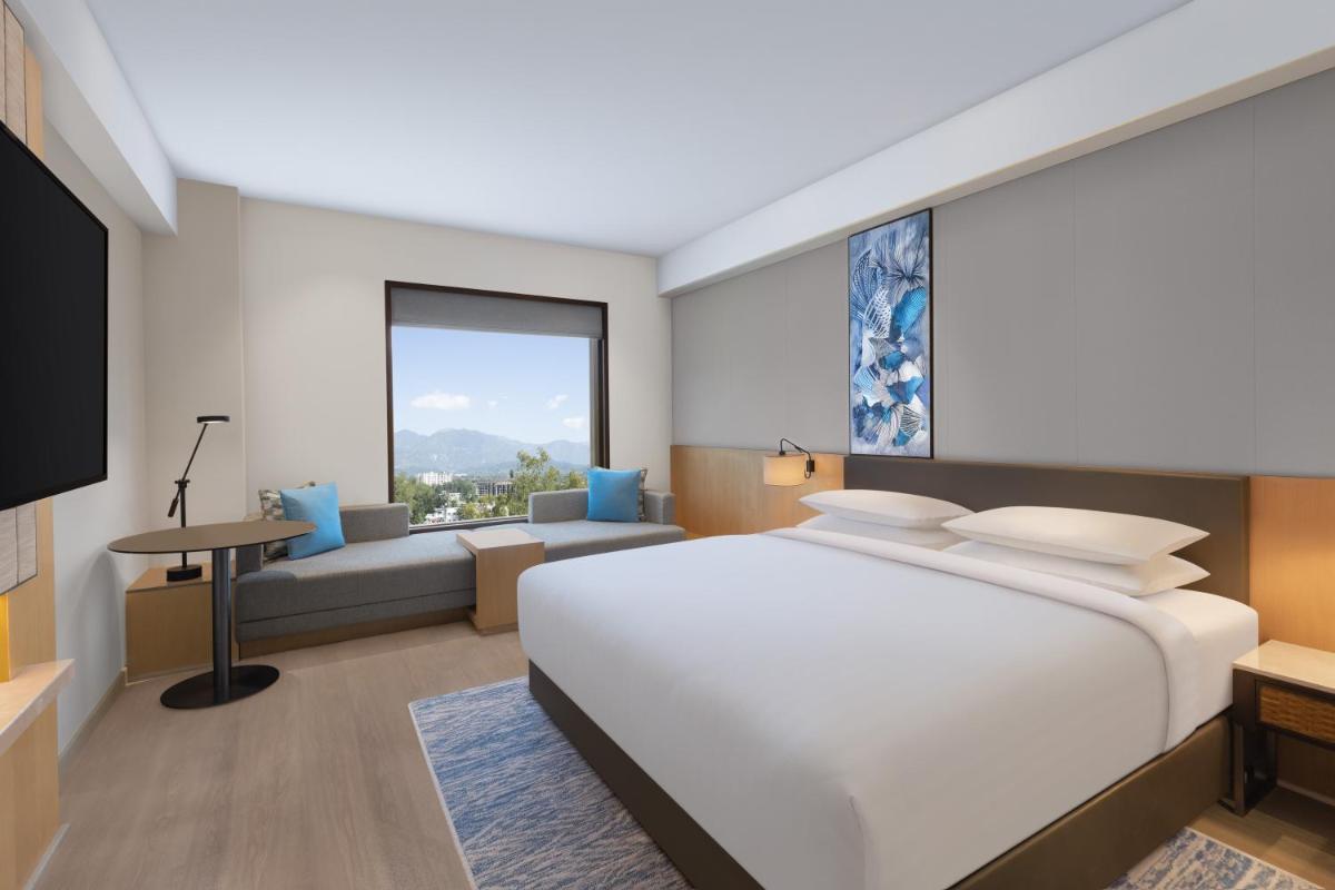 a bedroom with a large white bed and a living room at Fairfield by Marriott Dehradun in Dehradun