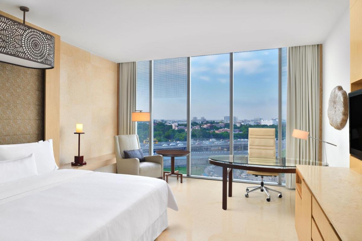 a hotel room with a bed and a desk with a view at The Westin Gurgaon, New Delhi in Gurgaon
