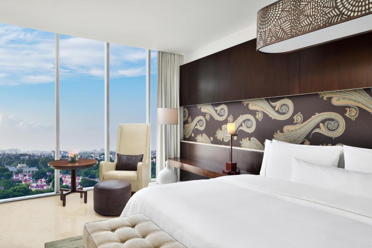 a hotel room with a bed and a chair and windows at The Westin Gurgaon, New Delhi in Gurgaon