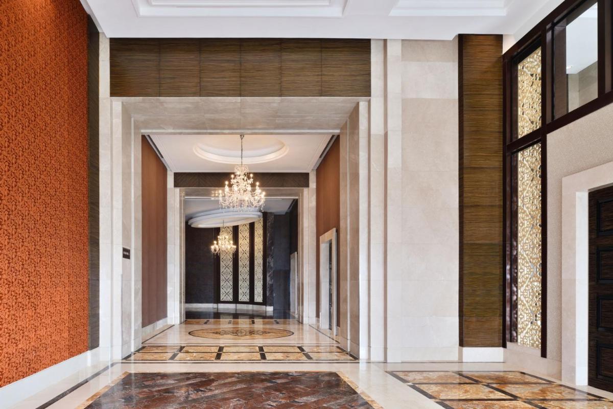a hallway with orange walls and a chandelier at The St. Regis Mumbai in Mumbai