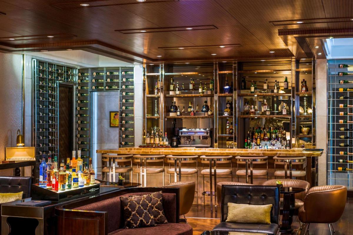 a bar with bar stools and shelves of wine bottles at The St. Regis Mumbai in Mumbai