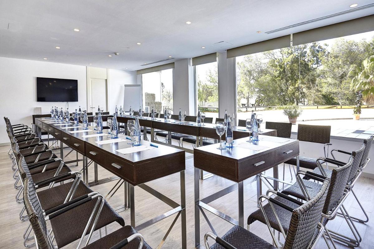 Una habitación grande con mesas, sillas y ventanas. en Grupotel Maritimo, en Puerto de Alcudia