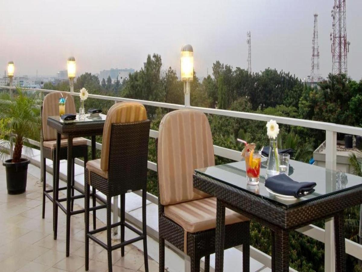 a table and chairs on a balcony with a view at Svenska Design Hotel, Electronic City, Bangalore in Bengaluru a table and chairs on a balcony with a view at Svenska Design Hotel, Electronic City, Bangalore in Bengaluru