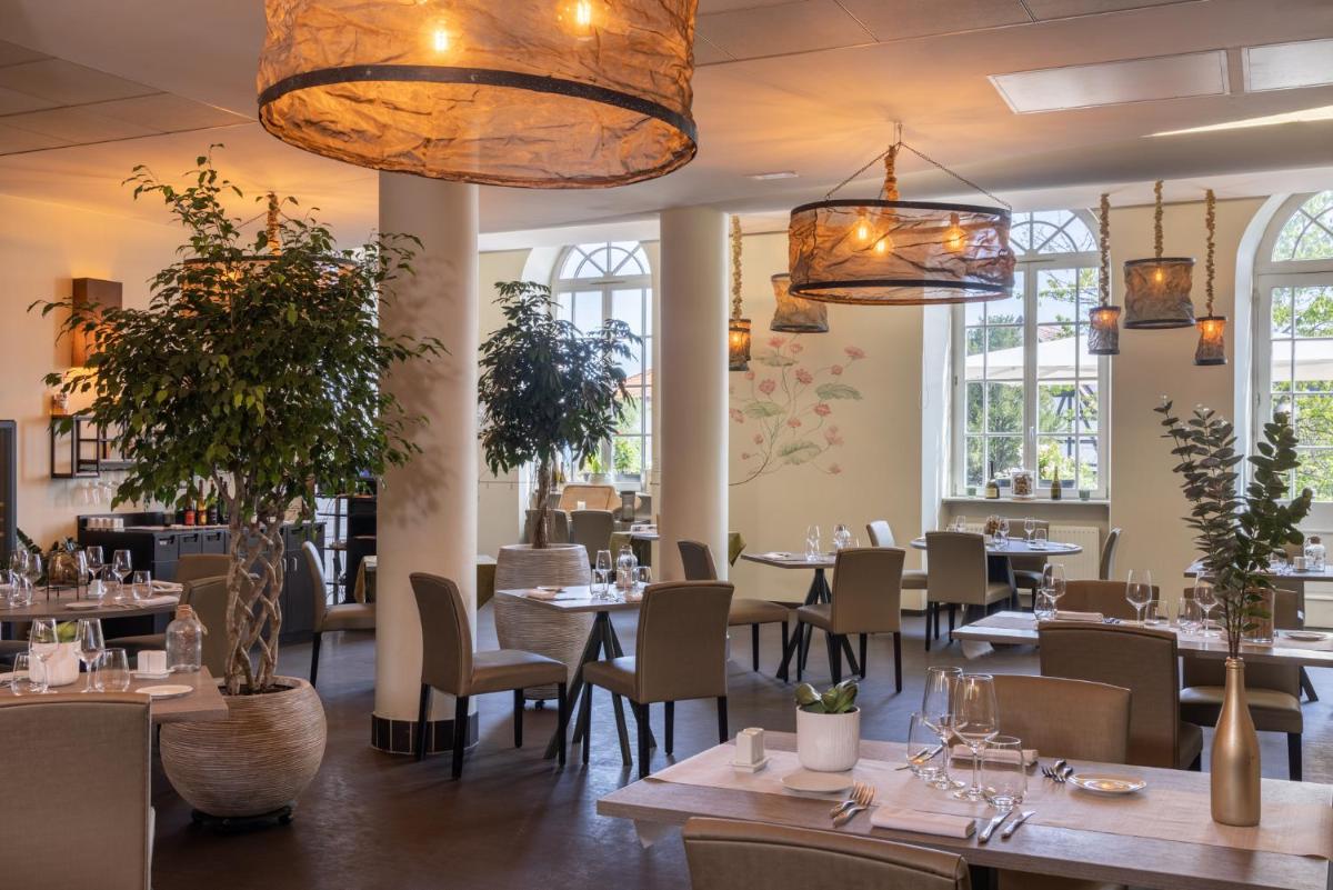 un restaurant avec des tables et des chaises et de grandes fenêtres dans l'établissement Hôtel Val-Vignes Colmar Haut-Koenigsbourg, The Originals Relais, à Saint-Hippolyte