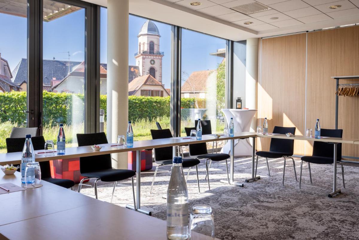 une salle de conférence avec des tables et des chaises et une tour d'horloge en arrière-plan dans l'établissement Hôtel Val-Vignes Colmar Haut-Koenigsbourg, The Originals Relais, à Saint-Hippolyte