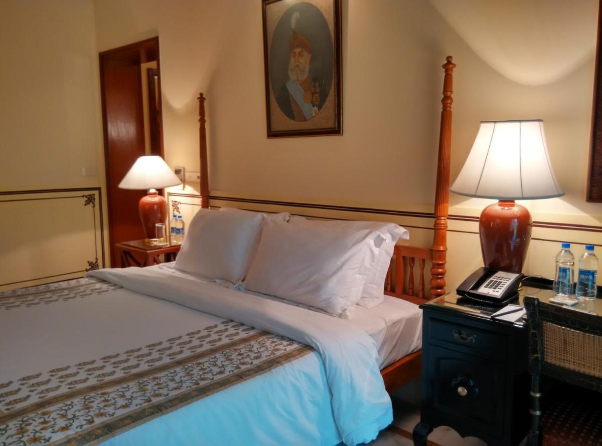 a bedroom with a bed and a lamp on a table at Jai Mahal Palace in Jaipur