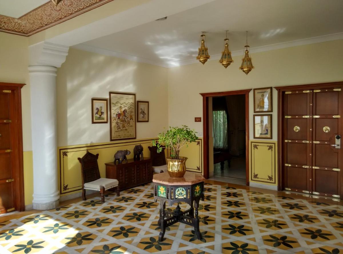 a living room with a table and a chair and a room at Jai Mahal Palace in Jaipur