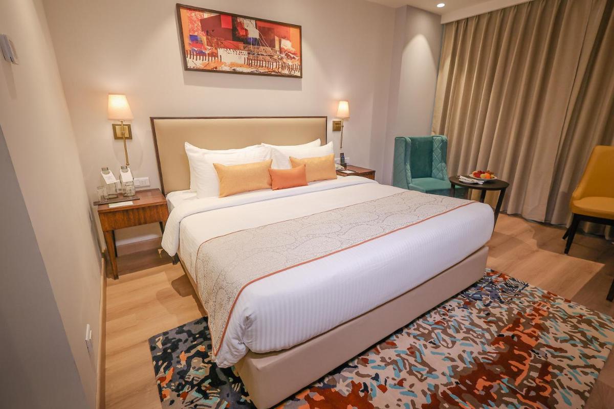 a hotel room with a large bed and a desk at Regenta Dehradun by Royal Orchid Hotels Limited in Dehradun