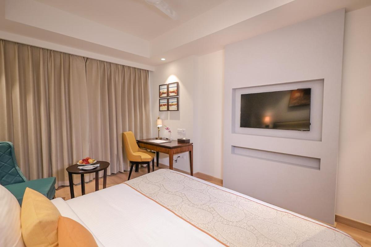 a hotel room with a bed and a desk and a television at Regenta Dehradun by Royal Orchid Hotels Limited in Dehradun