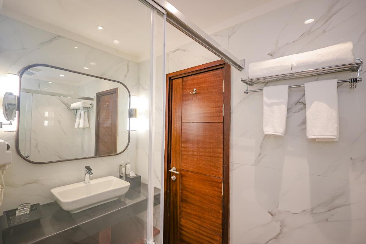 a bathroom with a sink and a mirror at Regenta Dehradun by Royal Orchid Hotels Limited in Dehradun
