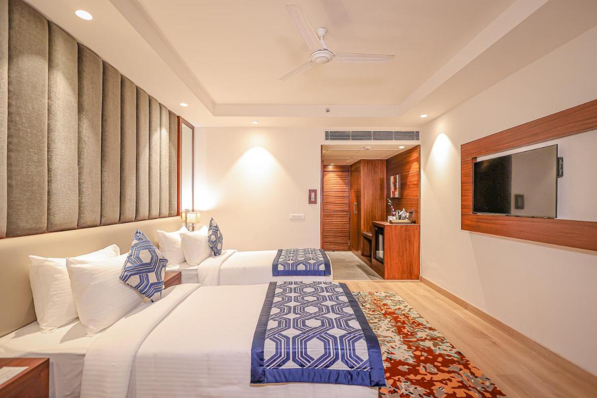a hotel room with two beds and a flat screen tv at Regenta Dehradun by Royal Orchid Hotels Limited in Dehradun
