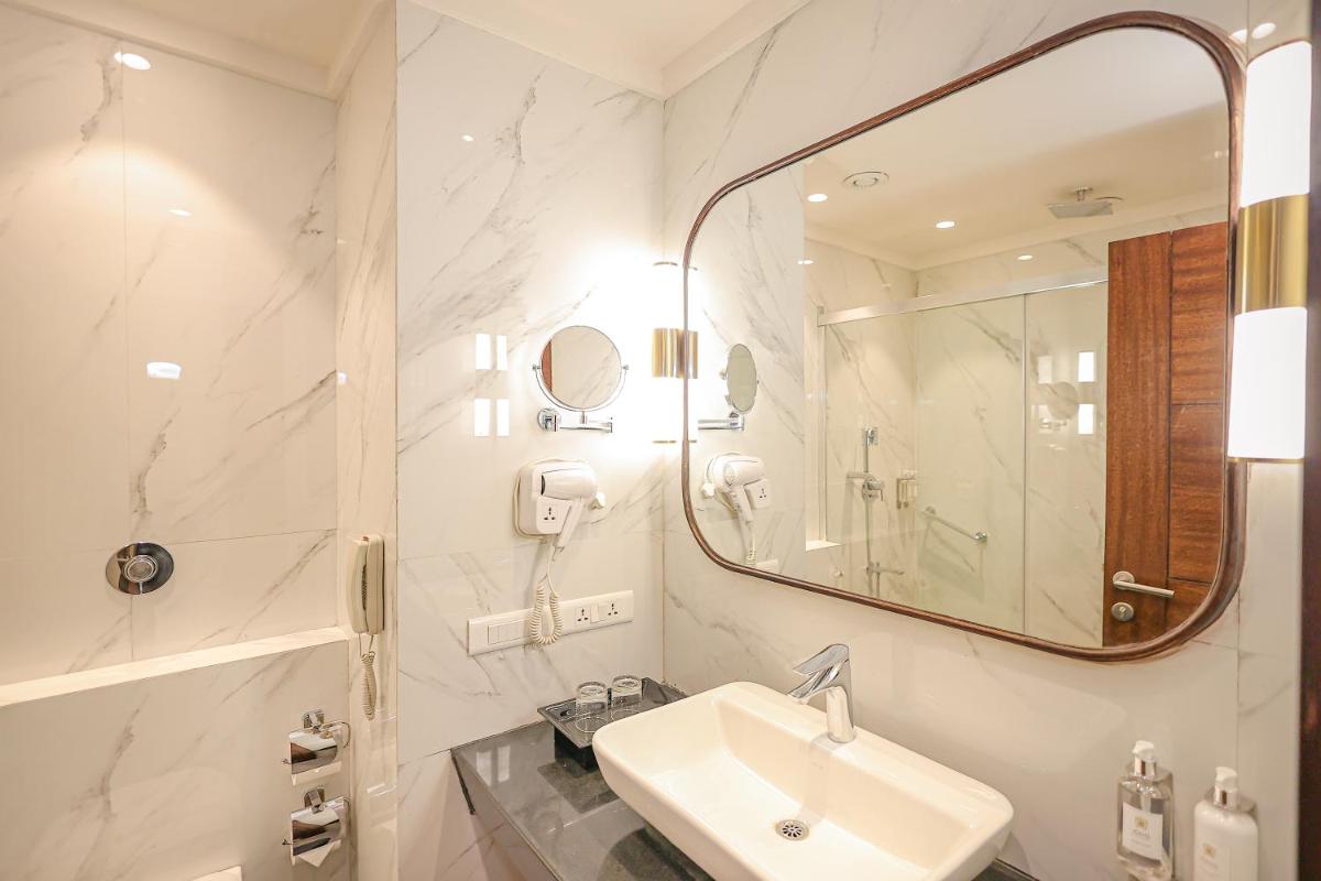 a white bathroom with a sink and a mirror at Regenta Dehradun by Royal Orchid Hotels Limited in Dehradun