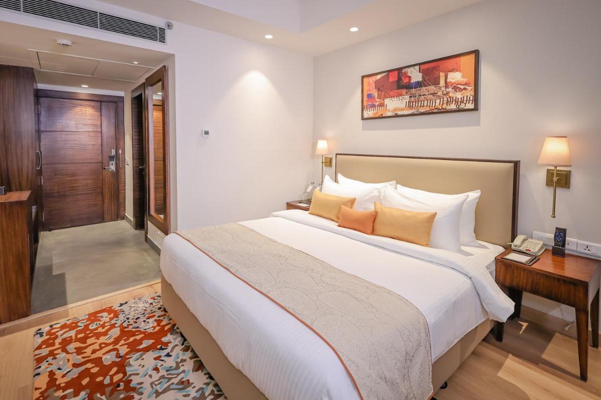 a bedroom with a large bed and a desk at Regenta Dehradun by Royal Orchid Hotels Limited in Dehradun