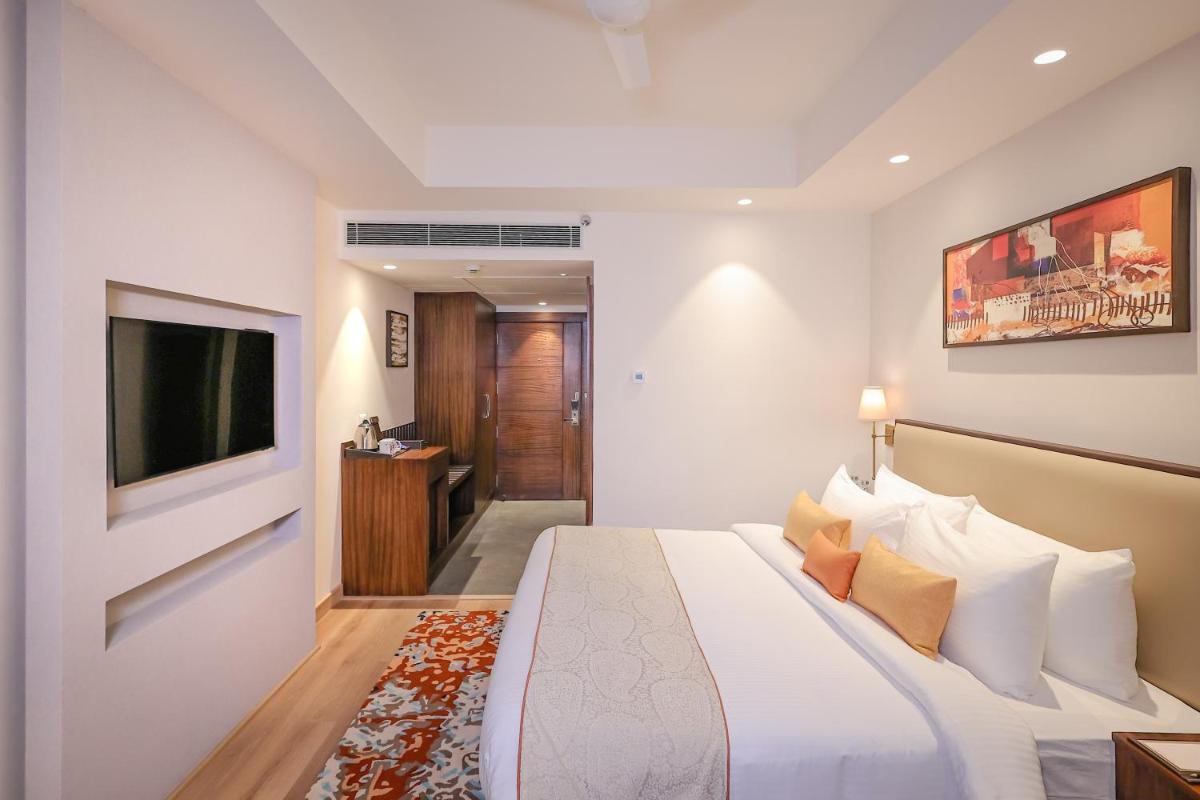 a bedroom with a large bed and a television at Regenta Dehradun by Royal Orchid Hotels Limited in Dehradun