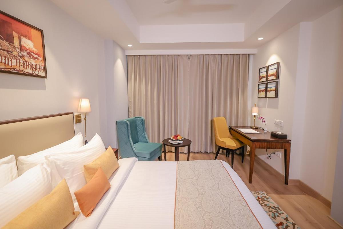 a hotel room with a bed and a desk at Regenta Dehradun by Royal Orchid Hotels Limited in Dehradun