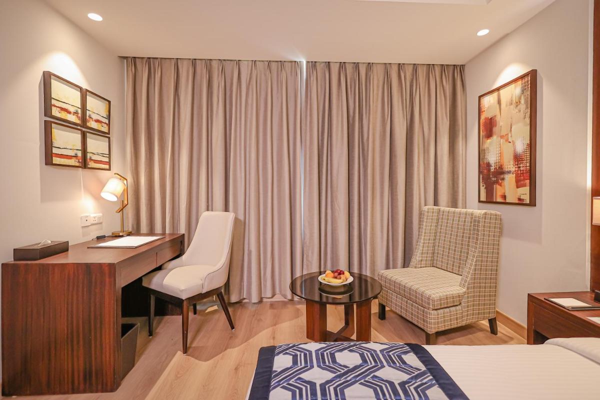 a hotel room with a desk and a bedroom at Regenta Dehradun by Royal Orchid Hotels Limited in Dehradun
