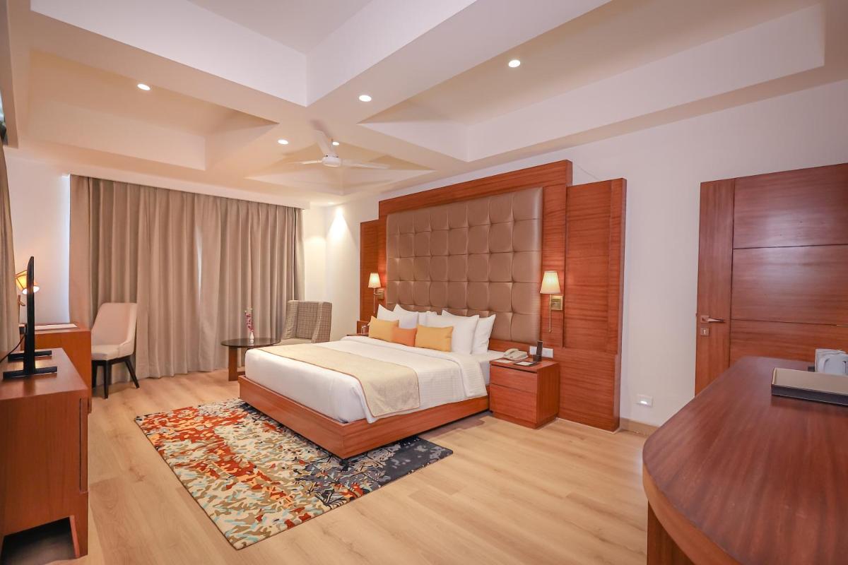 a hotel room with a bed and a desk at Regenta Dehradun by Royal Orchid Hotels Limited in Dehradun