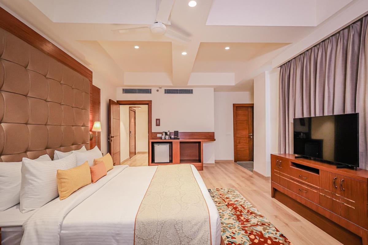 a bedroom with a large bed and a flat screen tv at Regenta Dehradun by Royal Orchid Hotels Limited in Dehradun
