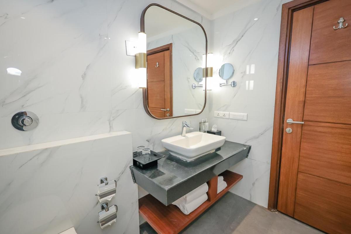a bathroom with a sink and a mirror at Regenta Dehradun by Royal Orchid Hotels Limited in Dehradun