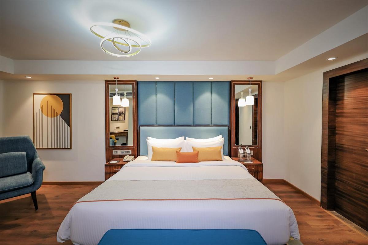 a bedroom with a large bed and a blue wall at Regenta Dehradun by Royal Orchid Hotels Limited in Dehradun