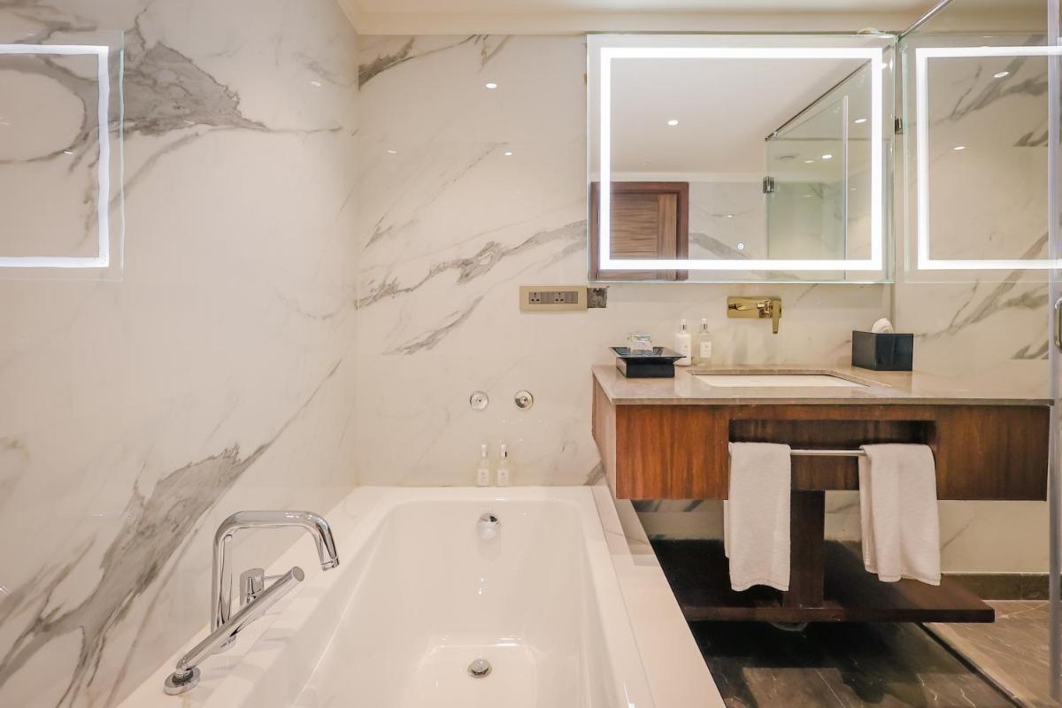 a white bathroom with a tub and a sink at Regenta Dehradun by Royal Orchid Hotels Limited in Dehradun
