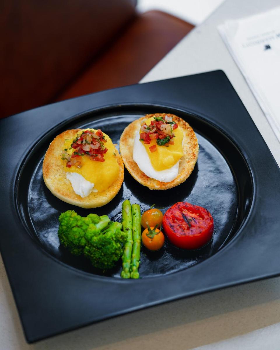 a black plate with two sandwiches and vegetables on it at JW Marriott Mumbai Sahar Airport in Mumbai a black plate with two sandwiches and vegetables on it at JW Marriott Mumbai Sahar Airport in Mumbai
