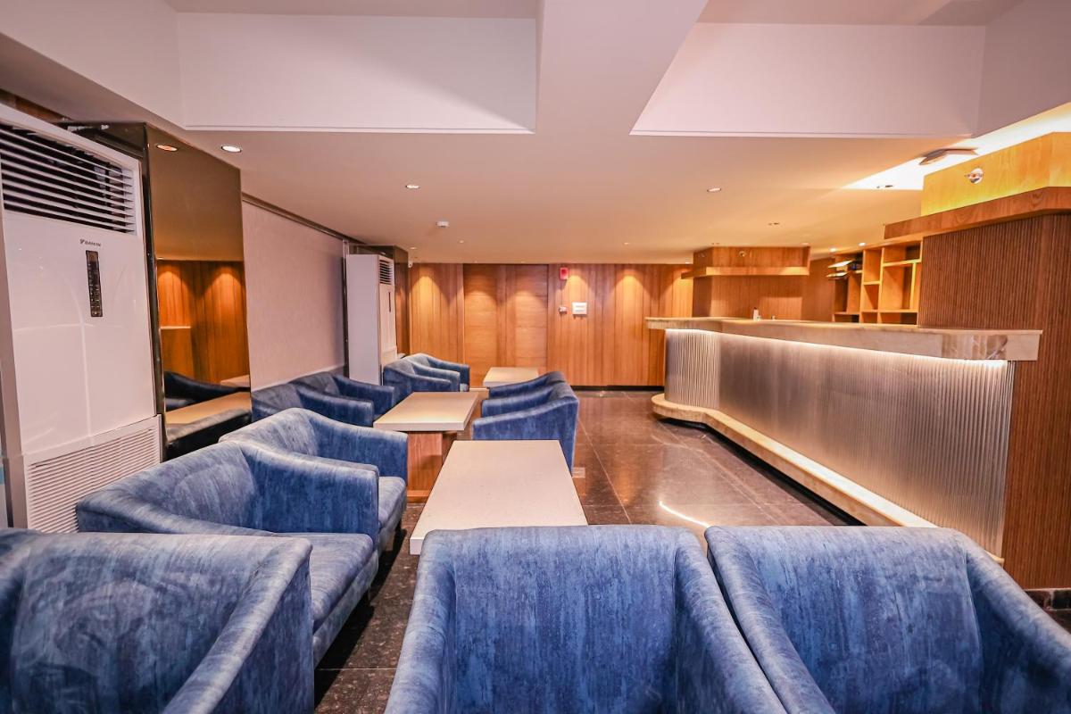 a waiting room with blue chairs and tables and a bar at Regenta Dehradun by Royal Orchid Hotels Limited in Dehradun