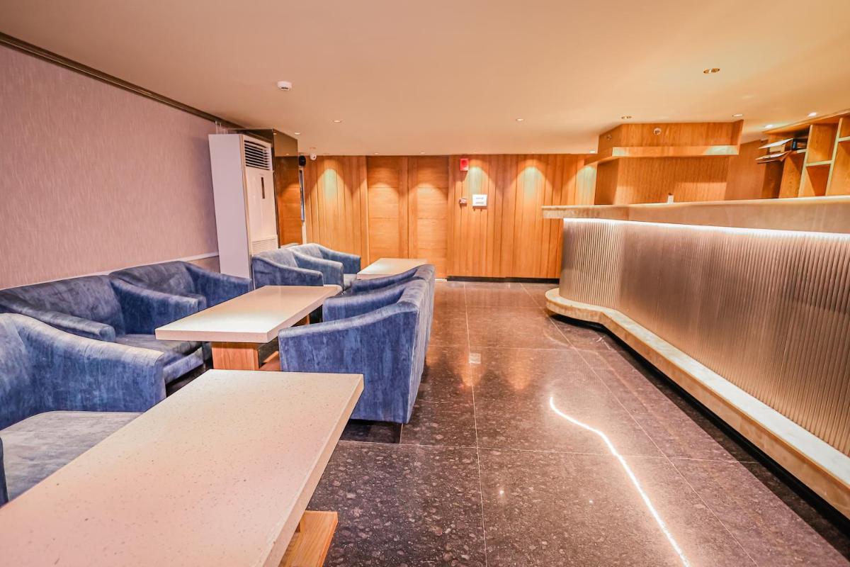 a waiting room with blue chairs and tables at Regenta Dehradun by Royal Orchid Hotels Limited in Dehradun