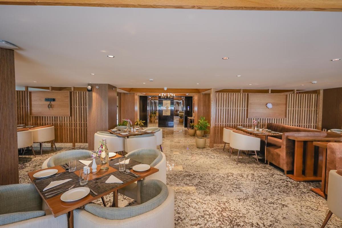 a restaurant with tables and chairs and a bar at Regenta Dehradun by Royal Orchid Hotels Limited in Dehradun