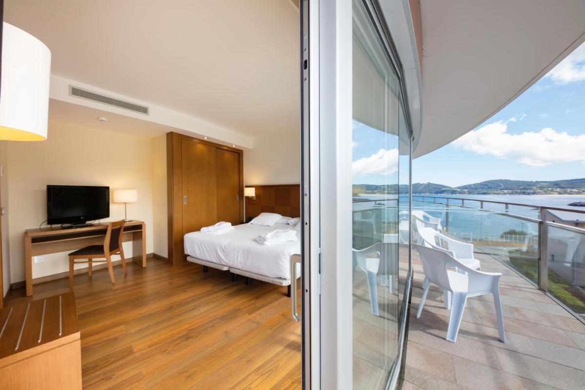 una habitación de hotel con una cama y un balcón en Hotel Thalasso Cantabrico Las Sirenas 4 Superior, en Viveiro 58 fotos más