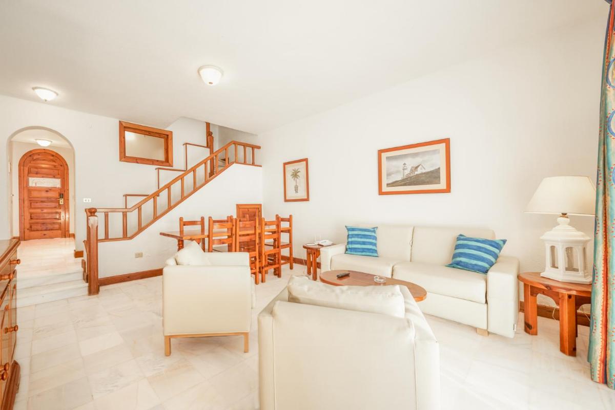 Una sala de estar con muebles blancos y una escalera. en Parque Santiago III Official, en Playa de las Américas 137 fotos más
