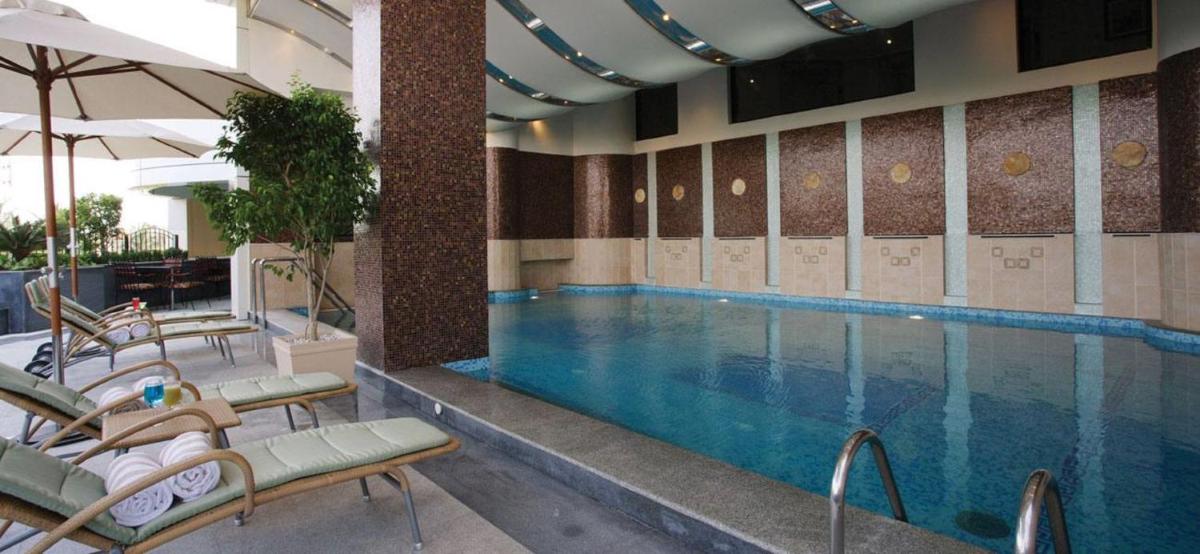 a swimming pool in a hotel room with chairs and a pool at The Accord Metropolitan in Chennai