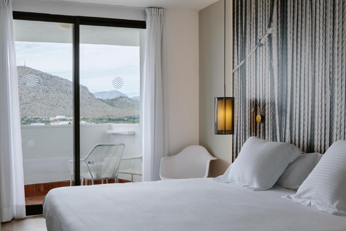 Un dormitorio con una cama blanca y una ventana grande. en Bordoy Alcudia Bay - Adults Only, en Puerto de Alcudia