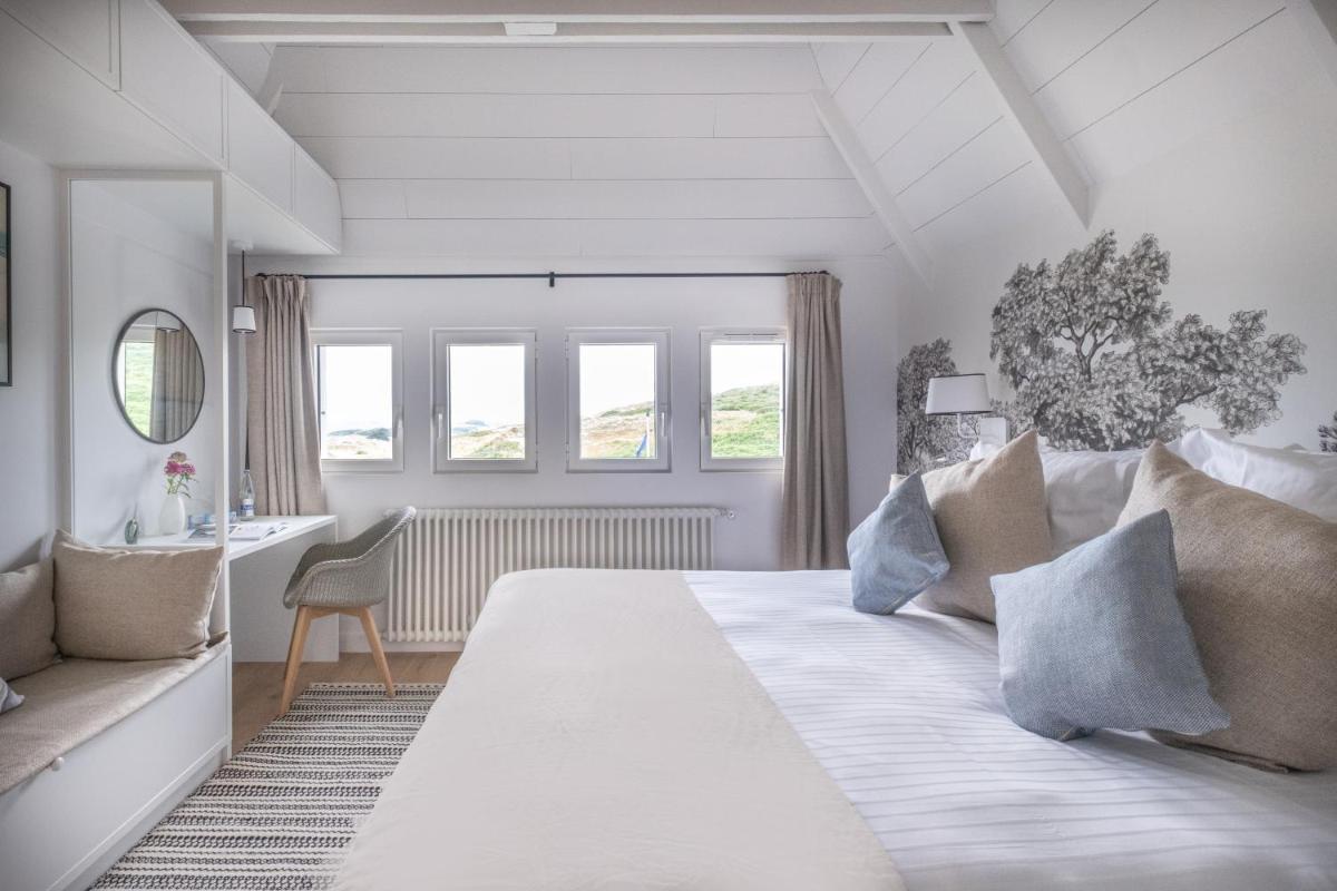 une chambre blanche avec un grand lit et un bureau dans l'établissement Hôtel de la Plage, à Plonévez-Porzay