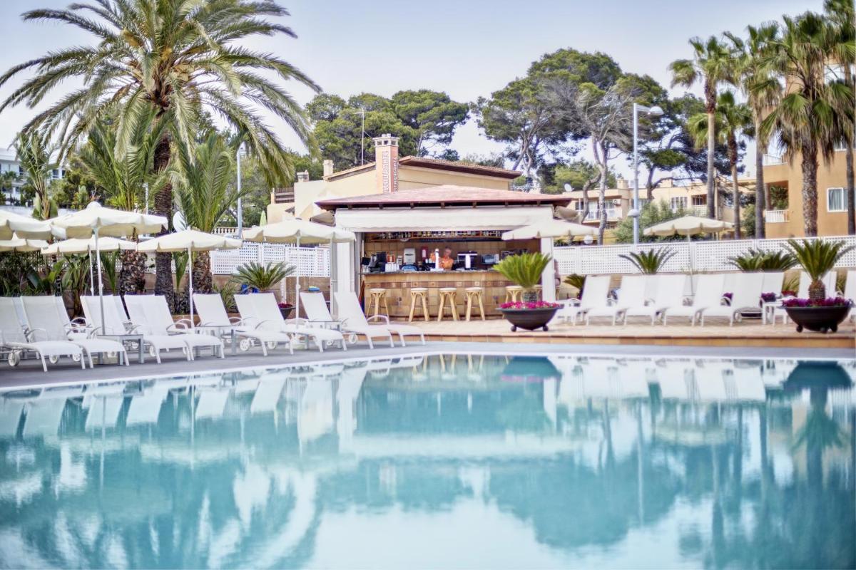 una piscina con sillas blancas y un bar en Grupotel Acapulco Playa - Adults Only, en Playa de Palma